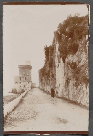 Terracine. Vue de la partie haute du village, avec une femme au 1er plan et une tour carrée à l'arrière-plan.
