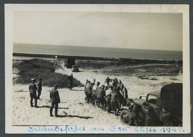 Camion enlisé dans le sable. Des soldats tirent le véhicule.